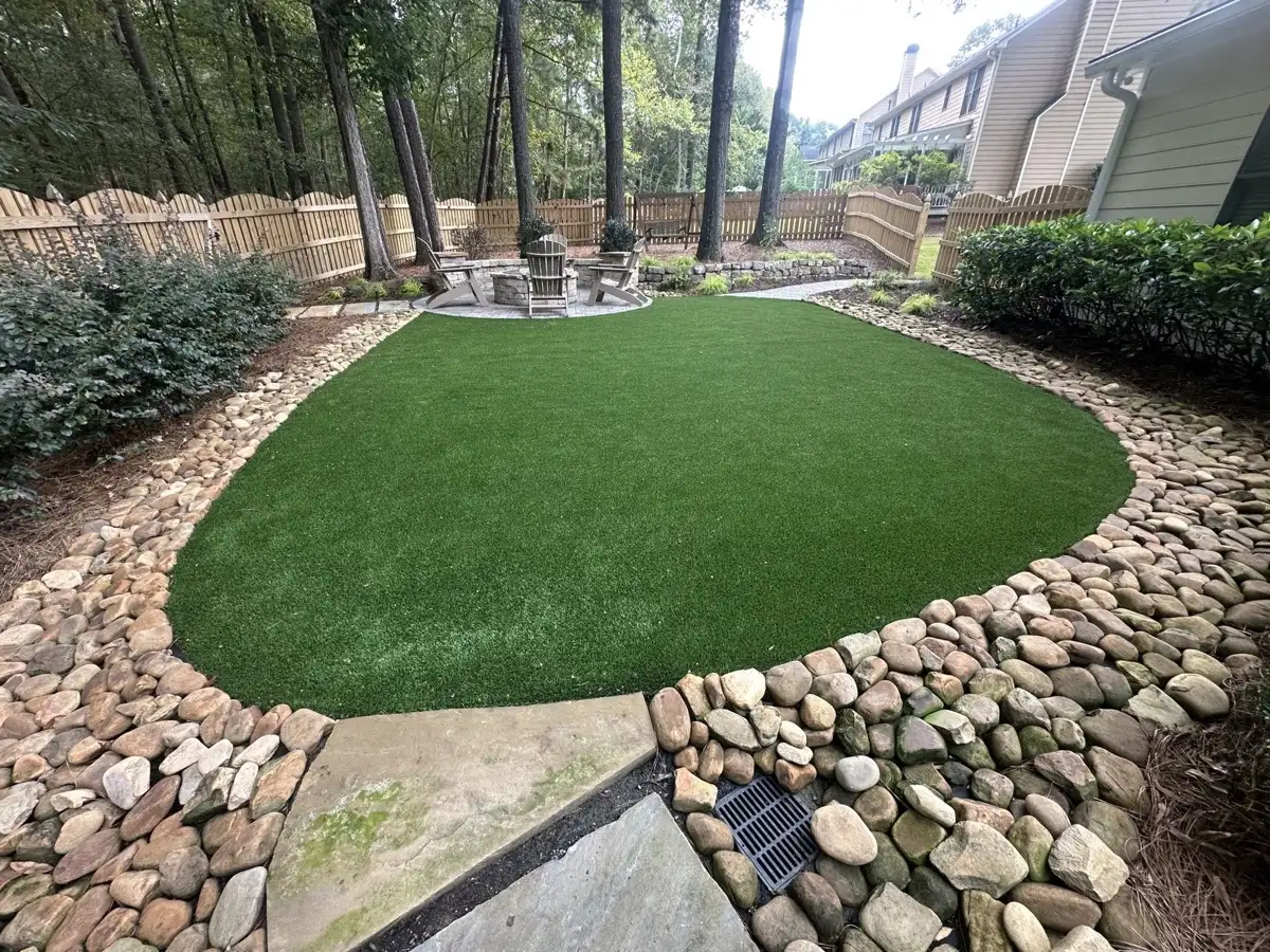 Artificial turf backyard bordered with river rock