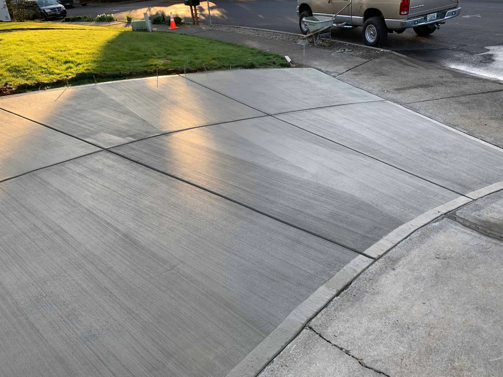 Finished broom-finish concrete driveway with saw-cut control joints beside the curb