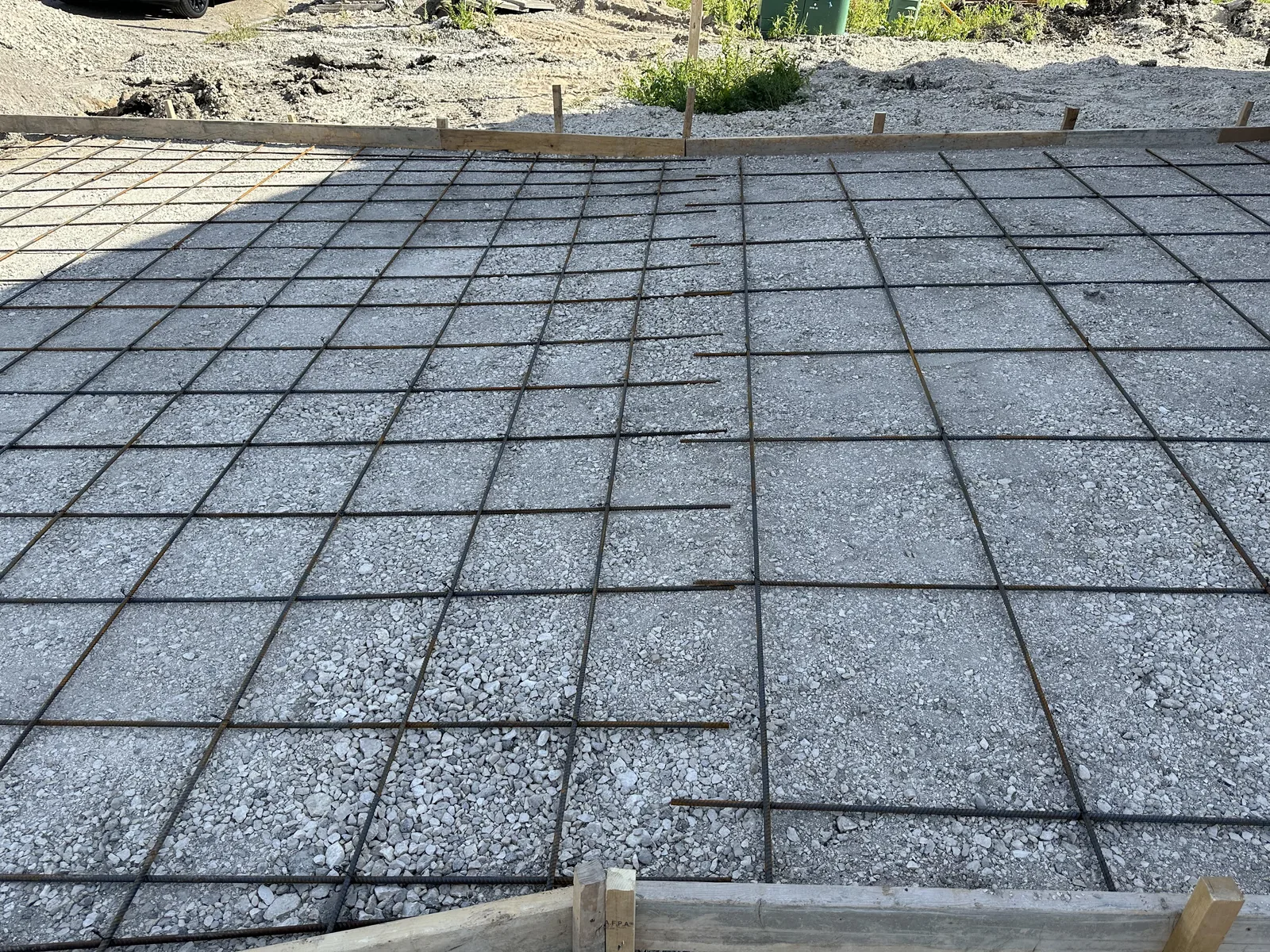 Steel reinforcement grid set on a gravel base inside driveway forms before a concrete pour