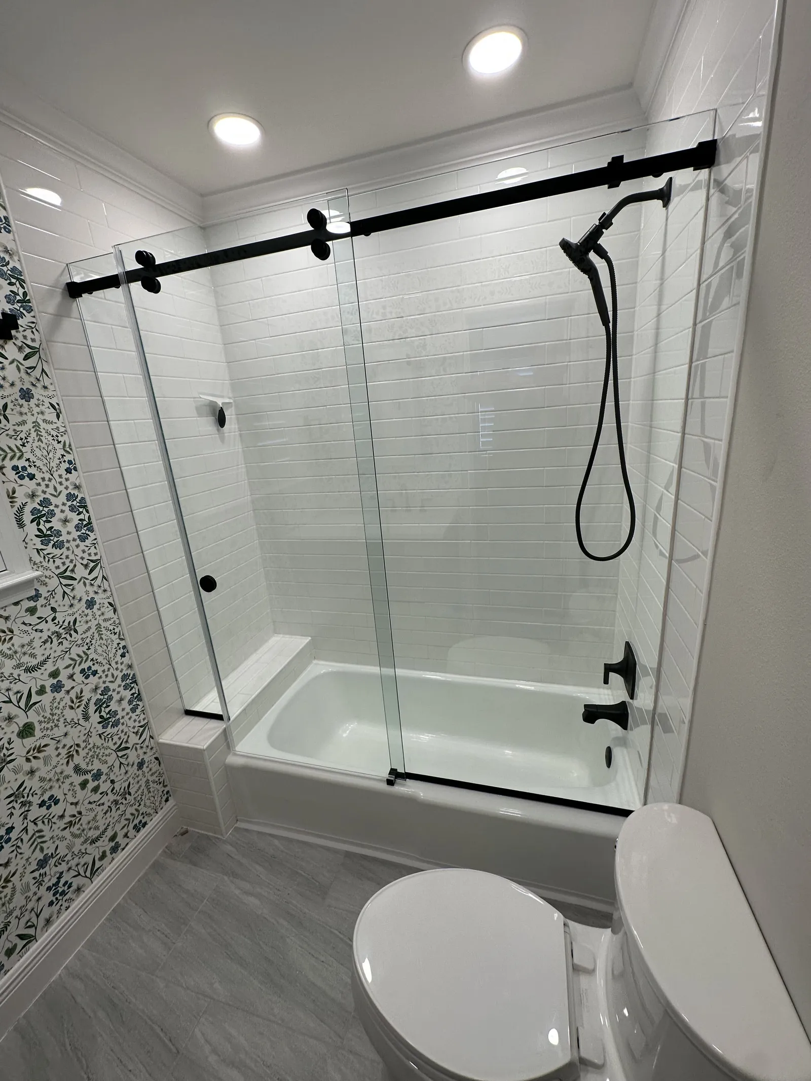 Tub-shower combo with white subway tile walls and a sliding glass door in a Houston bathroom, part of a shower remodeling job
