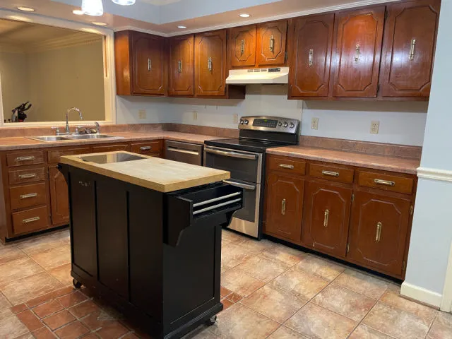 Houston kitchen before its remodel, with original oak cabinets, a closed layout and a rolling island cart, the kind of layout a load-bearing wall removal opens up