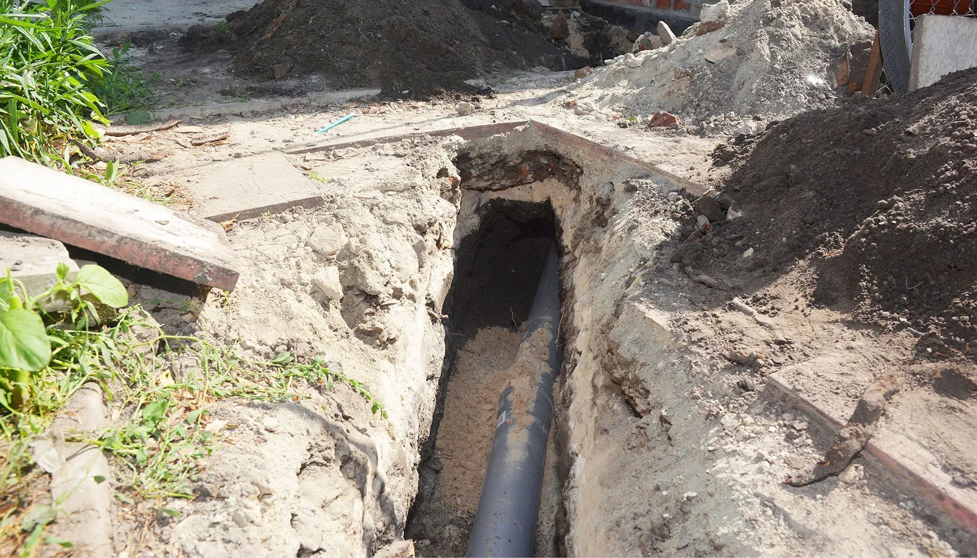 Open trench with new sewer pipe set at grade