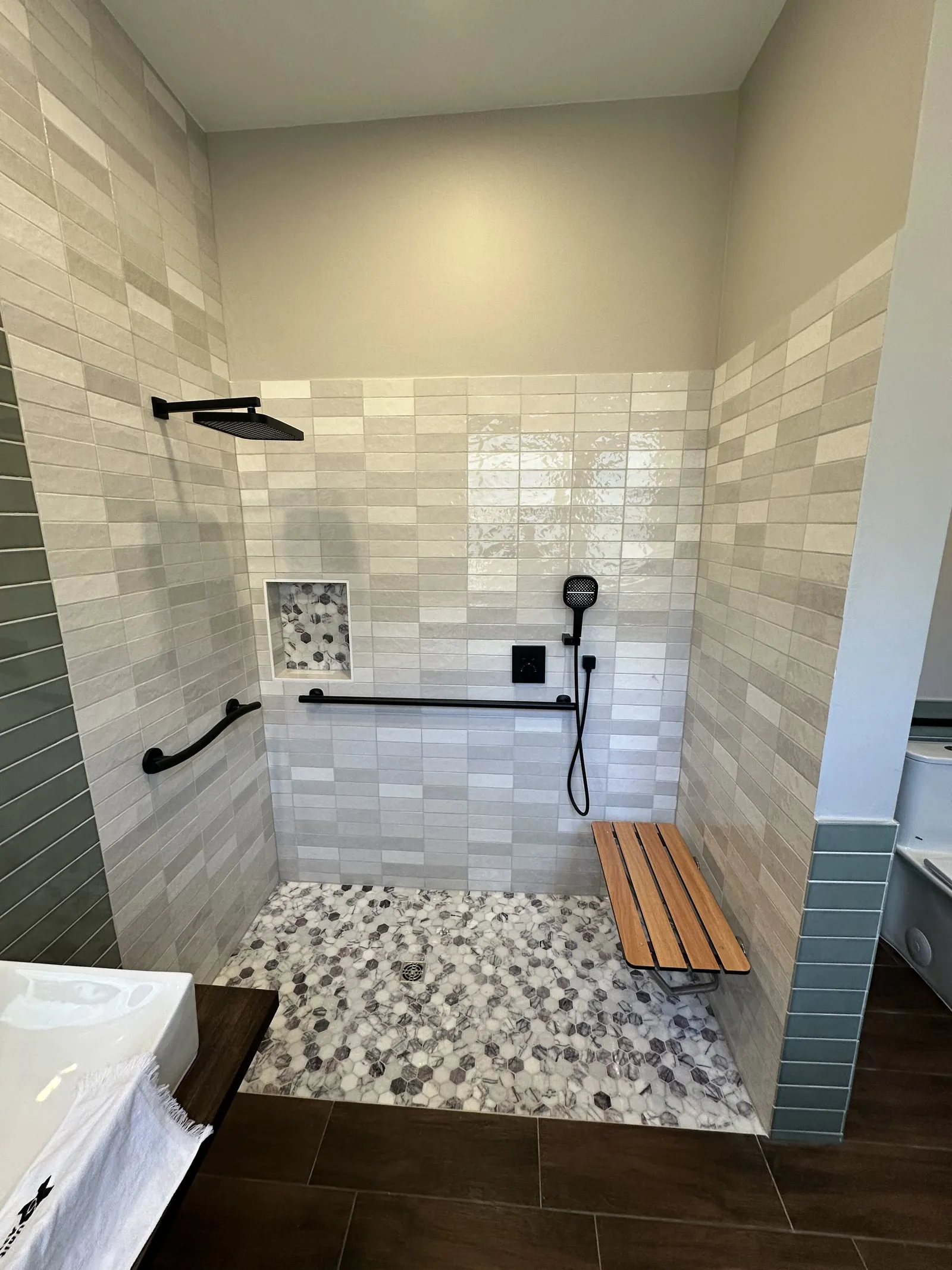 Curbless walk-in shower with teak bench built for an accessible Houston bathroom